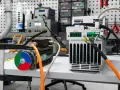 Warsztat z elektroniką, gdzie trwa eksploatacja maszyn. Widoczne silniki, zasilacze i narzędzia.