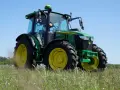 Zielony traktor John Deere 5095 M, z mocą 100km, gotowy do pracy na polu.