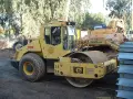 Żółty walec drogowy BOMAG BW 213D-3 gotowy do budowy drogi. W tle koparka Samsung Caterpillar.
