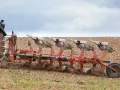 Ciągnik z pługiem orze pole. Widać pracujące lemiesze, które odwracają ziemię. Prędkość orki jest optymalna dla tej maszyny.