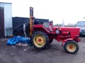Czerwony traktor z ładowarką czołową, gotowy do pracy. Może posłużyć do budowy masztu do ciągnika.