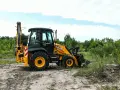Żółta koparko-ładowarka JCB 4CX na placu budowy. Maszyna gotowa do pracy, a jej spalanie jest optymalne dla tego typu zadań.