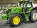 Zielony traktor marki John Deere 6155 M, gotowy do pracy na polu.