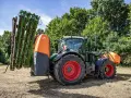Zielony traktor z zamontowanym opryskiwaczem polowym, gotowy do pracy.