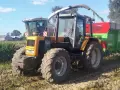 Żółty ciągnik Renault 120.54 z przyczepą podczas żniw kukurydzy. Pytanie o jaki olej do silnika MWM Renault jest tu na miejscu.