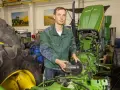 Mechanik z częścią John Deere, być może szuka informacji o john deere kody serwisowe, aby naprawić traktor.