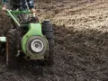 Rolnik używa jednoosiowego ciągnika z pługiem do orki. Różne rodzaje pługów pomagają przygotować ziemię pod uprawę.