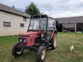 Czerwony Zetor 5011 na trawie, obok budynków gospodarczych. Zastanawiasz się nad jego spalaniem?