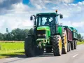 Zielony traktor z przyczepą jedzie po drodze. Zastanawiasz się, ile pali traktor?