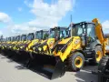 Rząd żółtych koparko-ładowarek JCB stoi na placu.