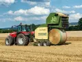 Czerwony traktor Massey Ferguson 6180 z prasą Krone Vario Pack na polu. Dane techniczne tej maszyny pozwalają na efektywne belowanie.