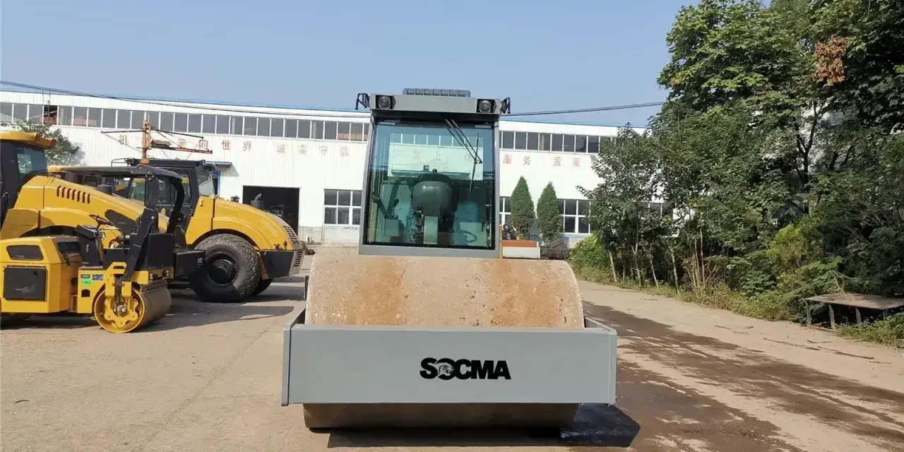 Nowy walec maszyna SOCMA gotowy do pracy na budowie. Obok stoją inne żółte maszyny budowlane.