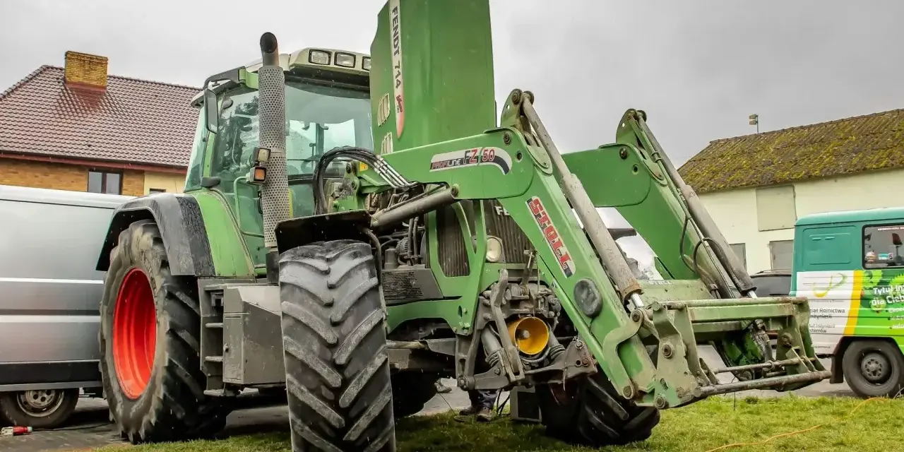 Zielony ciągnik Fendt 714 Vario z ładowaczem czołowym. Dane techniczne tego modelu są imponujące.