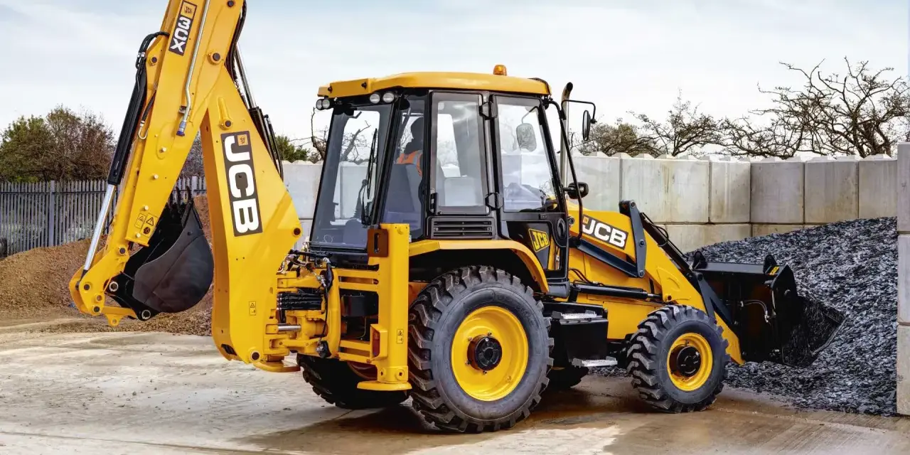 Żółty koparko-ładowarka JCB 3CX, gotowy do pracy. Jego waga pozwala na stabilność podczas kopania.