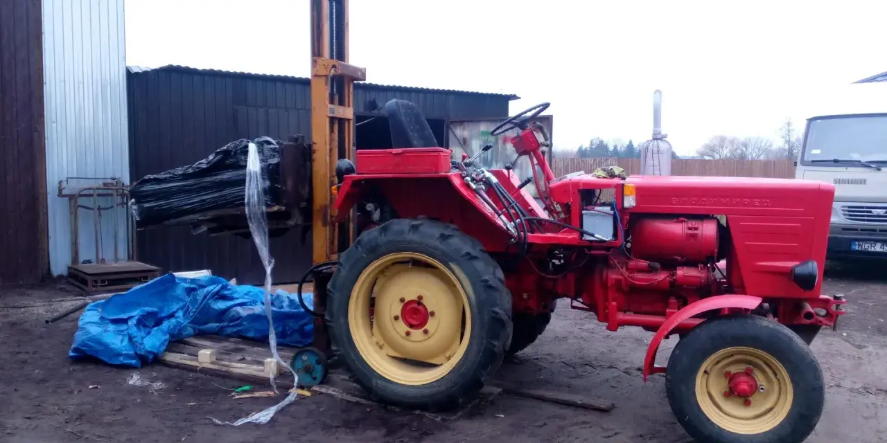 Czerwony traktor z ładowarką czołową, gotowy do pracy. Może posłużyć do budowy masztu do ciągnika.