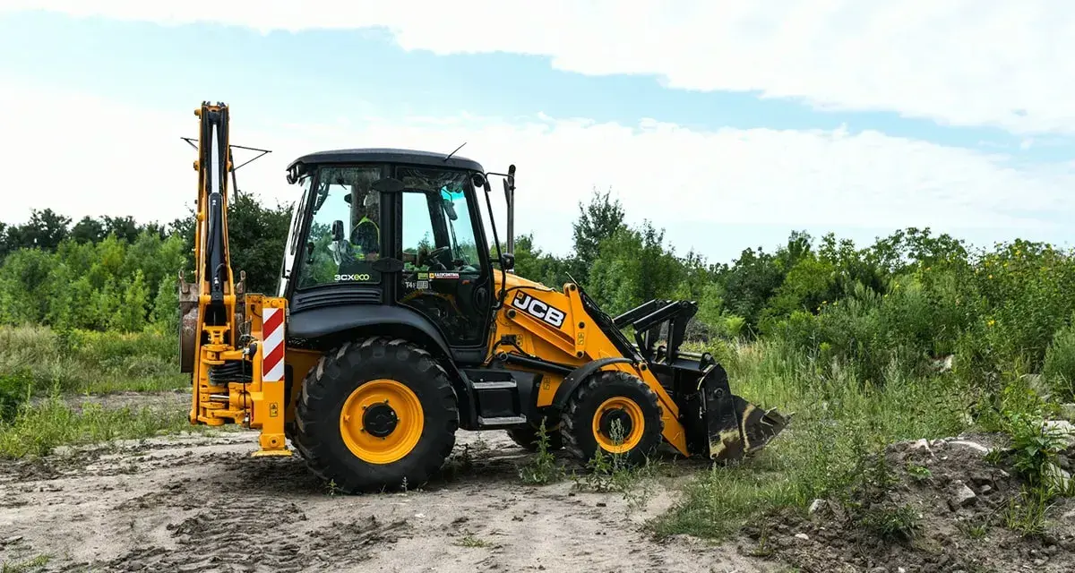 Żółta koparko-ładowarka JCB 4CX na placu budowy. Maszyna gotowa do pracy, a jej spalanie jest optymalne dla tego typu zadań.