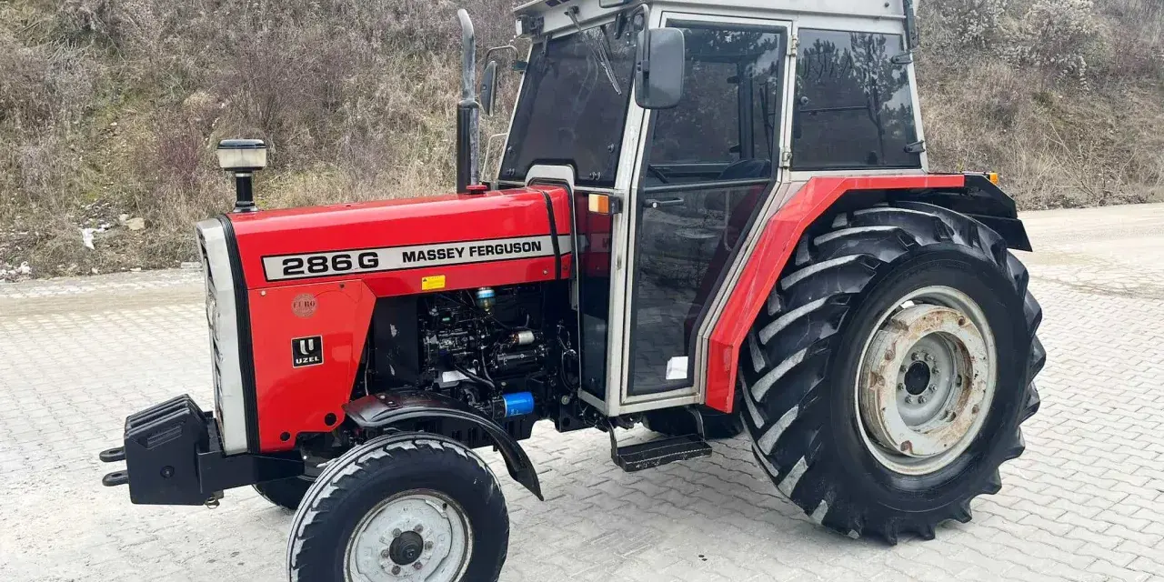 Czerwony Massey Ferguson 286G z kabiną, gotowy do pracy. Jego solidna konstrukcja i moc zapewniają niezawodność.