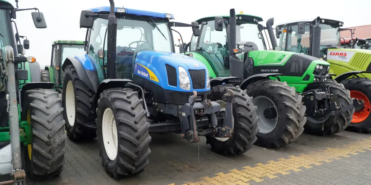 Rząd nowoczesnych traktorów: niebieski New Holland, zielony Deutz-Fahr i żółty Claas. Zastanawiasz się, ile motogodzin to dużo dla takiej maszyny?