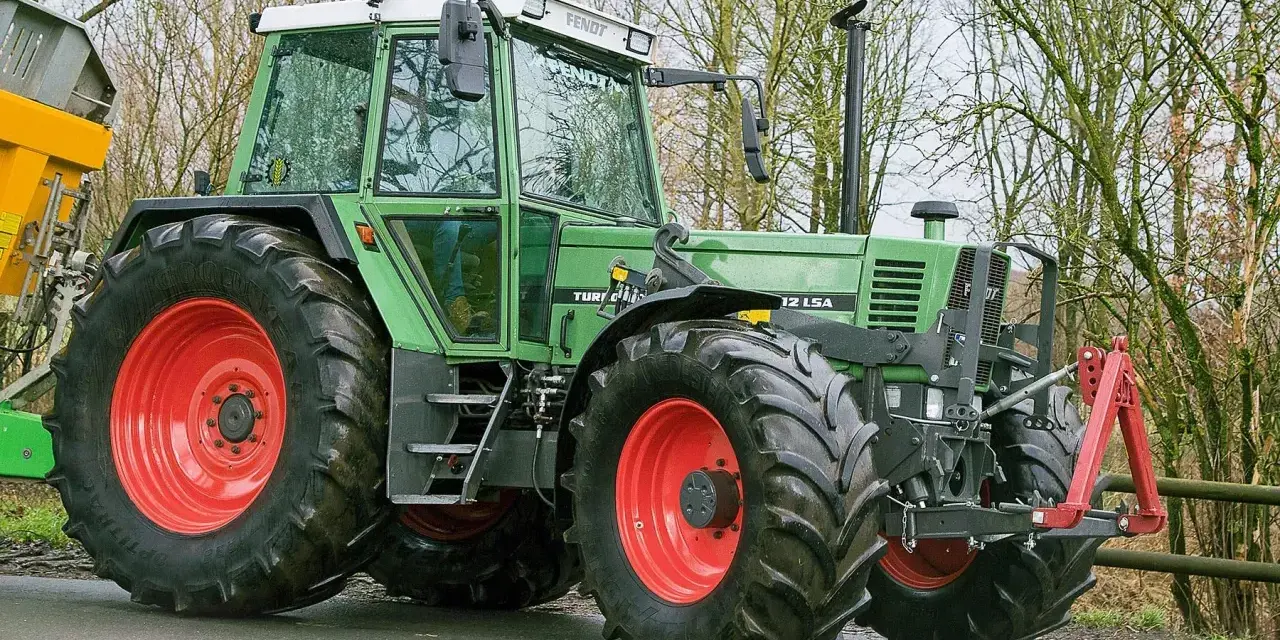 Zielony traktor Fendt 615 LSA z czerwonymi felgami, gotowy do pracy. Poznaj jego dane techniczne!