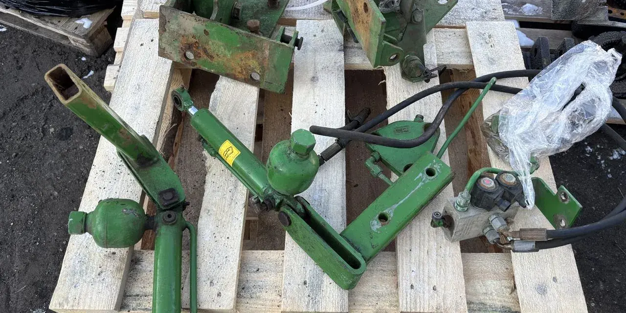 Części do amortyzacji kabiny John Deere: siłownik, wsporniki i elementy hydrauliczne.