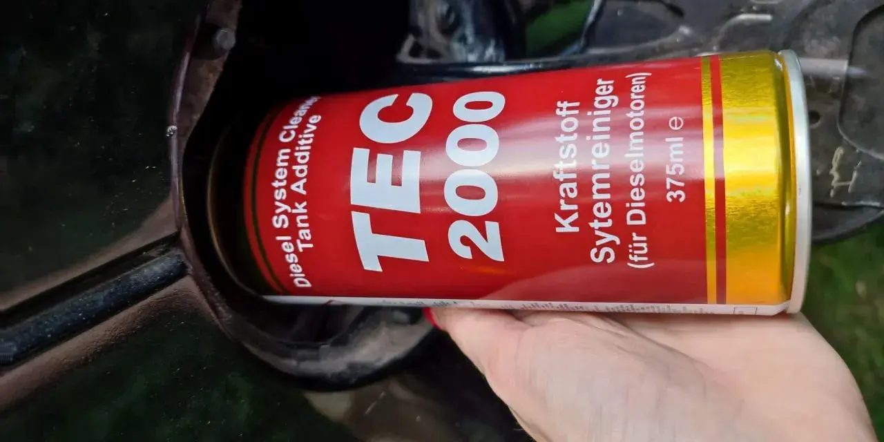 Ręka wlewa dodatek do paliwa TEC 2000 do baku, by zapobiec problemom z wodą w paliwie.