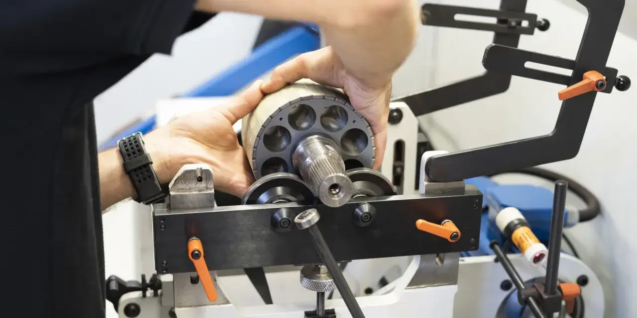 Ręce montują element wirnika pompy hydraulicznej, który jest częścią układu elektrycznego.