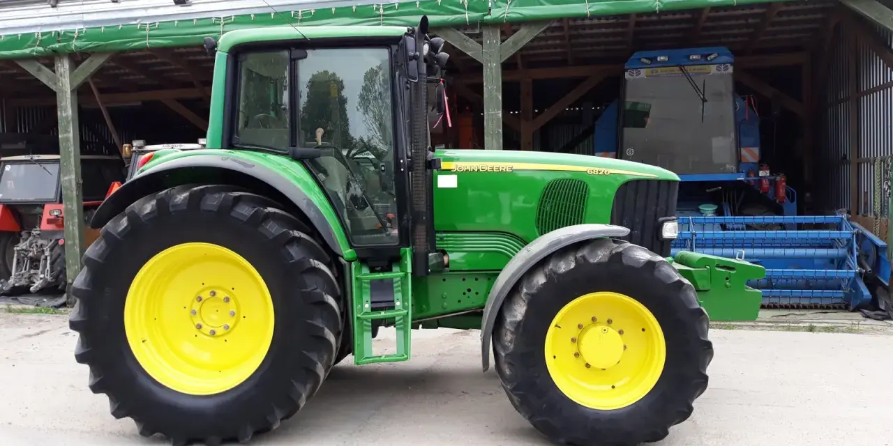 Zielony traktor John Deere 6820, z żółtymi felgami, gotowy do pracy. Dane techniczne tego modelu są imponujące.
