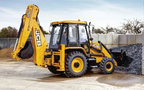 Żółty koparko-ładowarka JCB 3CX, gotowy do pracy. Jego waga pozwala na stabilność podczas kopania.