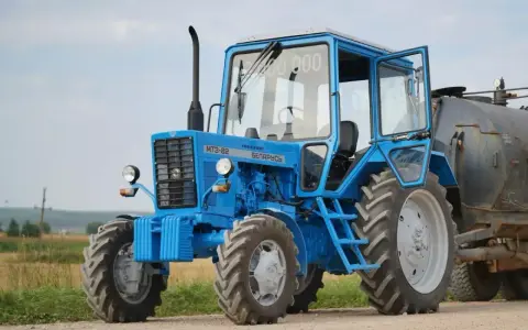Niebieski ciągnik 4x4 MTZ-82 "Biełaruś" z otwartymi drzwiami, gotowy do pracy w polu. Idealny ciągnik 4x4 do 30 tys.