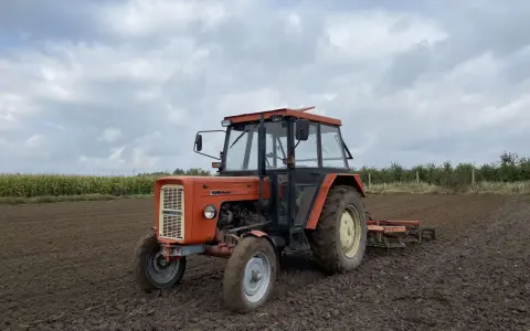 Pomarańczowy Ursus C-360 na polu, gotowy do pracy. Warto sprawdzić, ile oleju do silnika C-360 wlać przed sezonem.