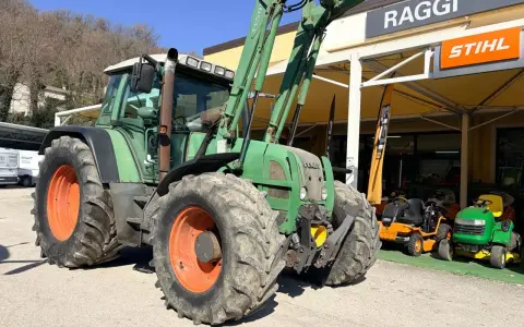Zielony traktor Fendt 716 z ładowaczem, obok sklepu Raggi. Dane techniczne tego modelu są imponujące.