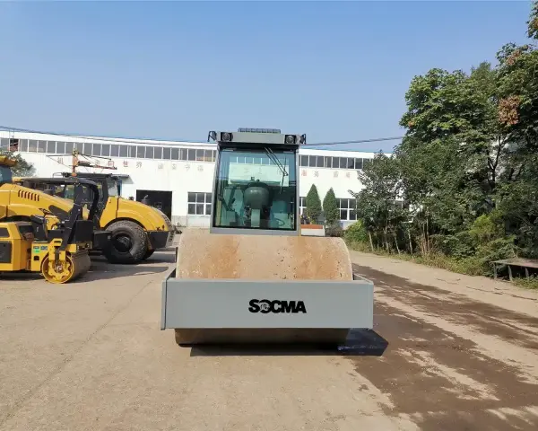 Nowy walec maszyna SOCMA gotowy do pracy na budowie. Obok stoją inne żółte maszyny budowlane.