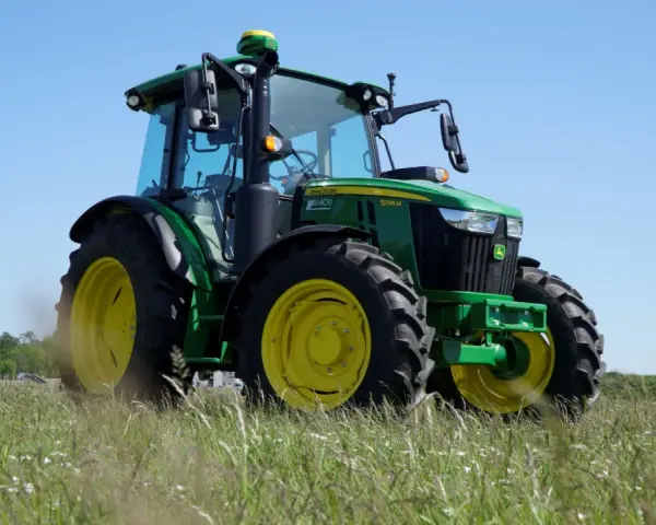 Zielony traktor John Deere 5095 M, z mocą 100km, gotowy do pracy na polu.