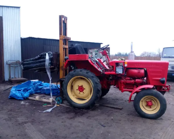 Czerwony traktor z ładowarką czołową, gotowy do pracy. Może posłużyć do budowy masztu do ciągnika.