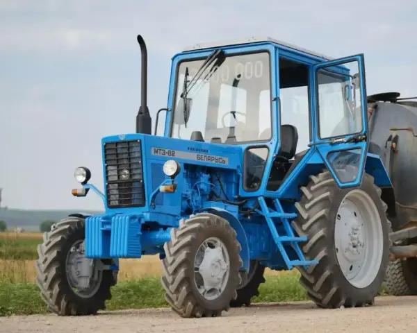 Niebieski ciągnik 4x4 MTZ-82 "Biełaruś" z otwartymi drzwiami, gotowy do pracy w polu. Idealny ciągnik 4x4 do 30 tys.