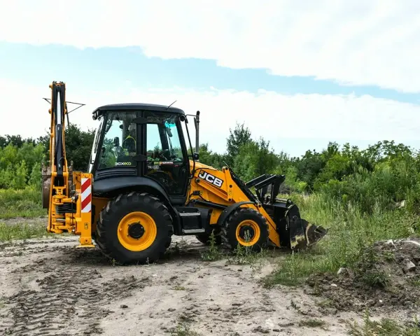 Żółta koparko-ładowarka JCB 4CX na placu budowy. Maszyna gotowa do pracy, a jej spalanie jest optymalne dla tego typu zadań.