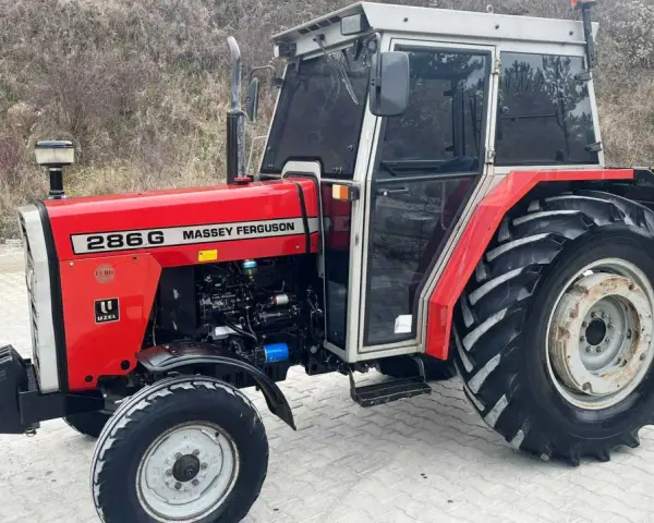 Czerwony Massey Ferguson 286G z kabiną, gotowy do pracy. Jego solidna konstrukcja i moc zapewniają niezawodność.