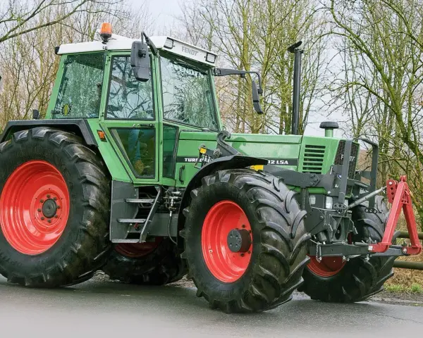 Zielony traktor Fendt 615 LSA z czerwonymi felgami, gotowy do pracy. Poznaj jego dane techniczne!