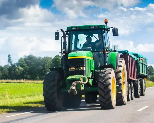 Zielony traktor z przyczepą jedzie po drodze. Zastanawiasz się, ile pali traktor?