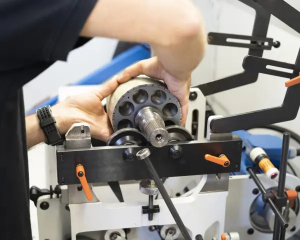 Ręce montują element wirnika pompy hydraulicznej, który jest częścią układu elektrycznego.