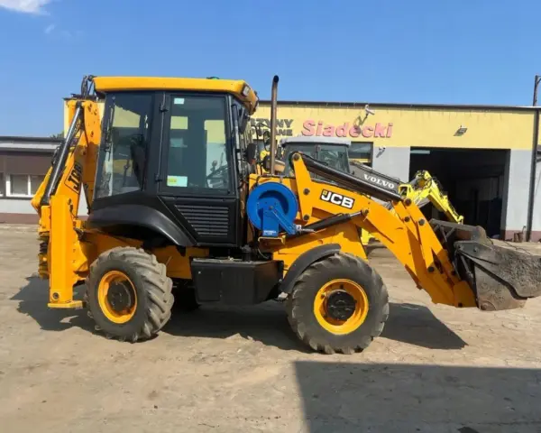 Żółta koparko-ładowarka JCB 2CX z ładowarką z przodu i koparką z tyłu, gotowa do pracy. Dane techniczne dostępne dla zainteresowanych.