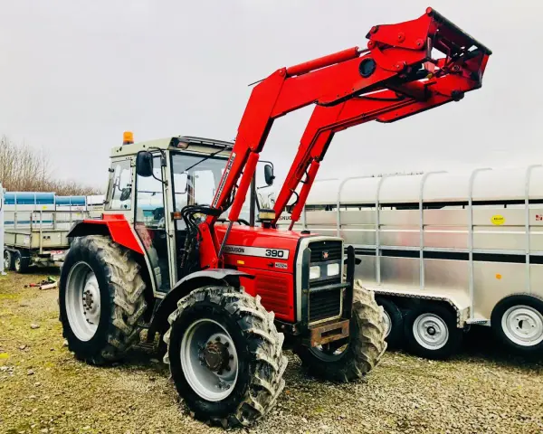 Czerwony ciągnik Massey Ferguson 390 z ładowaczem czołowym, gotowy do pracy. Dane techniczne tego modelu są imponujące.
