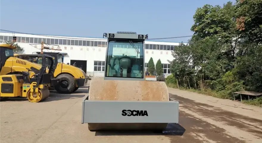Nowy walec maszyna SOCMA gotowy do pracy na budowie. Obok stoją inne żółte maszyny budowlane.