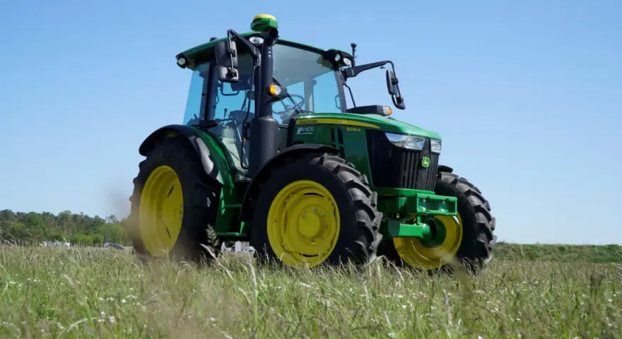 Zielony traktor John Deere 5095 M, z mocą 100km, gotowy do pracy na polu.