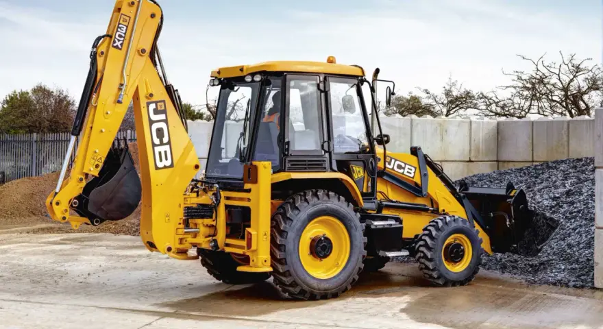 Żółty koparko-ładowarka JCB 3CX, gotowy do pracy. Jego waga pozwala na stabilność podczas kopania.