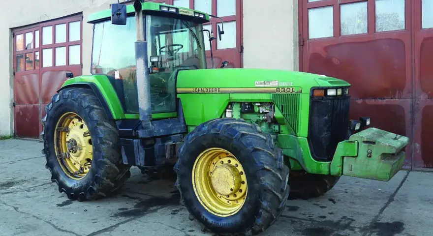 Zielony John Deere 8300C, potężna maszyna rolnicza, gotowa do pracy. Zastanawiasz się, ile motogodzin wytrzyma ciągnik tej klasy?
