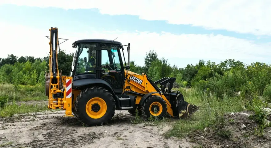 Żółta koparko-ładowarka JCB 4CX na placu budowy. Maszyna gotowa do pracy, a jej spalanie jest optymalne dla tego typu zadań.