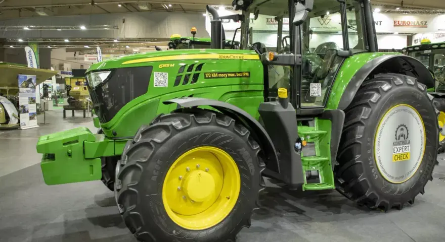 Zielony traktor marki John Deere 6155 M, gotowy do pracy na polu.