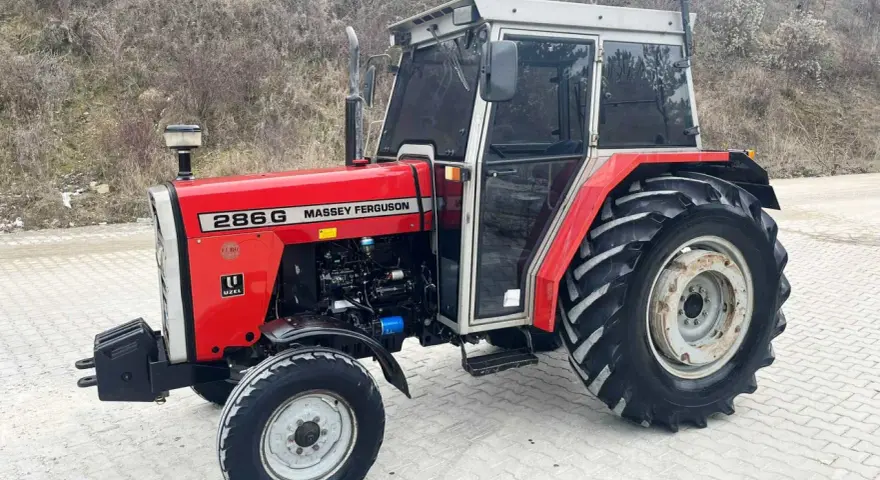 Czerwony Massey Ferguson 286G z kabiną, gotowy do pracy. Jego solidna konstrukcja i moc zapewniają niezawodność.