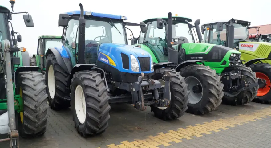 Rząd nowoczesnych traktorów: niebieski New Holland, zielony Deutz-Fahr i żółty Claas. Zastanawiasz się, ile motogodzin to dużo dla takiej maszyny?